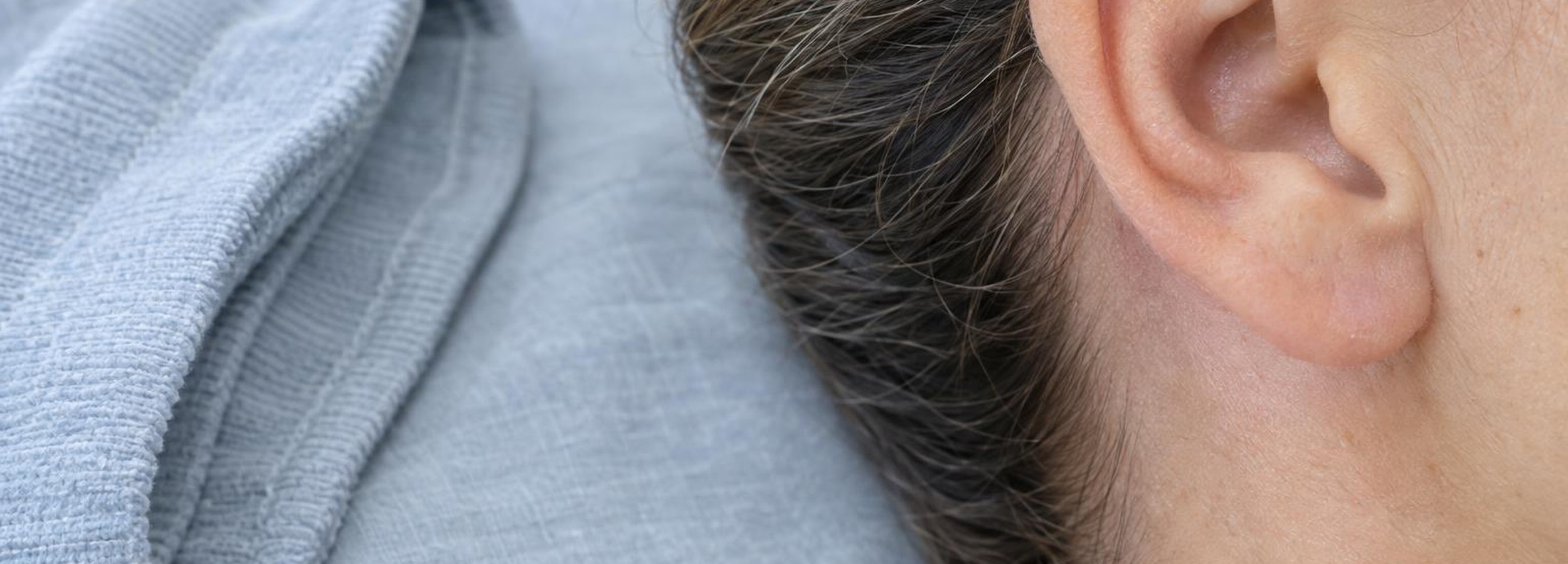 Otoplastia: recuperación real semana a semana 4 Pabellón auricular de perfil, sin rostro reconocible, en un entorno clínico sobrio tras una otoplastia.